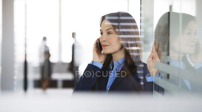 Donna d'affari che parla al cellulare in ufficio — Foto stock