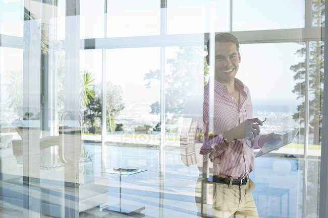 Бизнесмен улыбается в окно в современном офисе — стоковое фото
