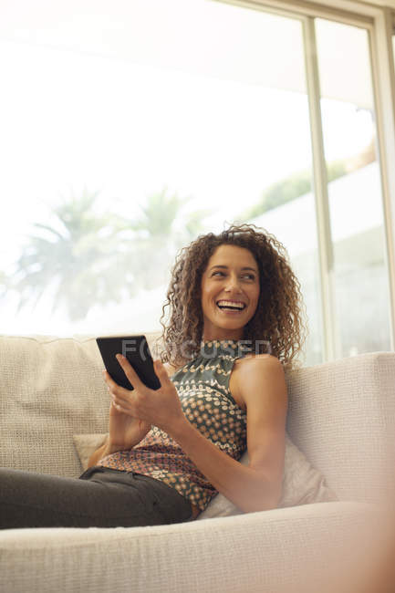 Молода приваблива жінка використовує планшетний комп'ютер на дивані — стокове фото