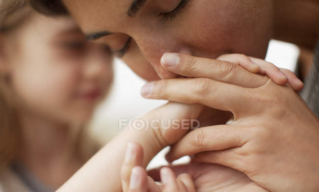 Closeup of mother kissing daughter in hand — Stock Photo