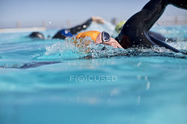 Confident and strong triathletes in wetsuit splashing in pool — Stock Photo