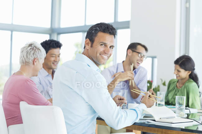 Hombre de negocios sonriendo en la reunión de almuerzo en la oficina moderna - foto de stock