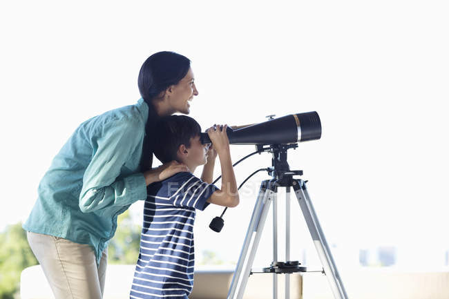 Madre e hijo usando telescopio - foto de stock
