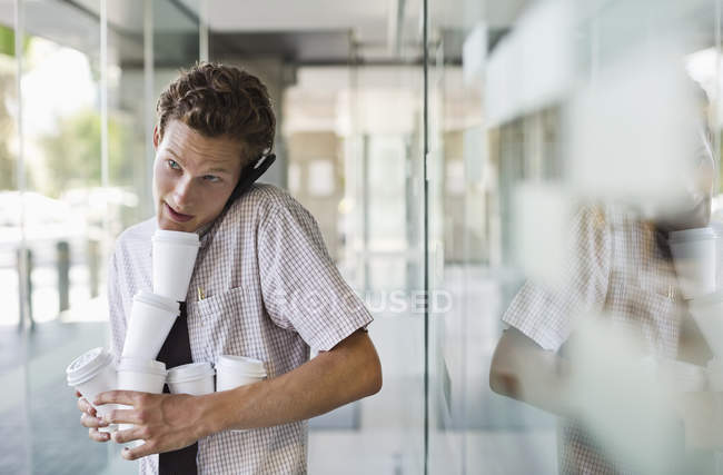 Businessman balancing coffees at modern office — Stock Photo