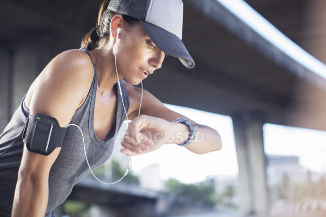 Woman looking at watch after exercising on city street — Stock Photo