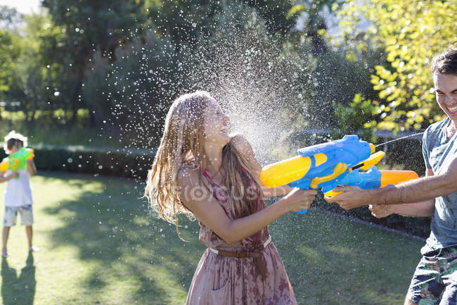 Casal brincando com armas de água no quintal — Fotografia de Stock