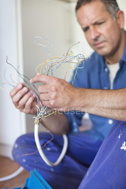 Eletricista caucasiano hábil examinando fios na cozinha — Fotografia de Stock