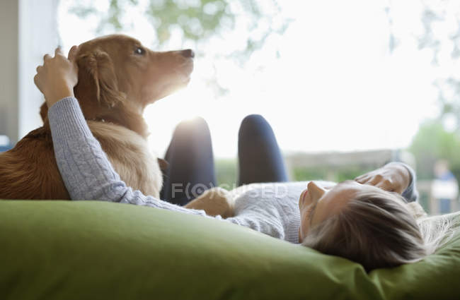 Cane da accarezzare donna sul letto a casa moderna — Foto stock