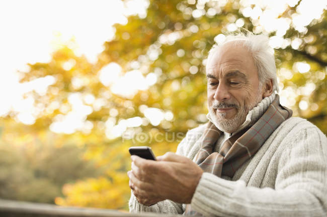 Older man using cell phone outdoors — Stock Photo