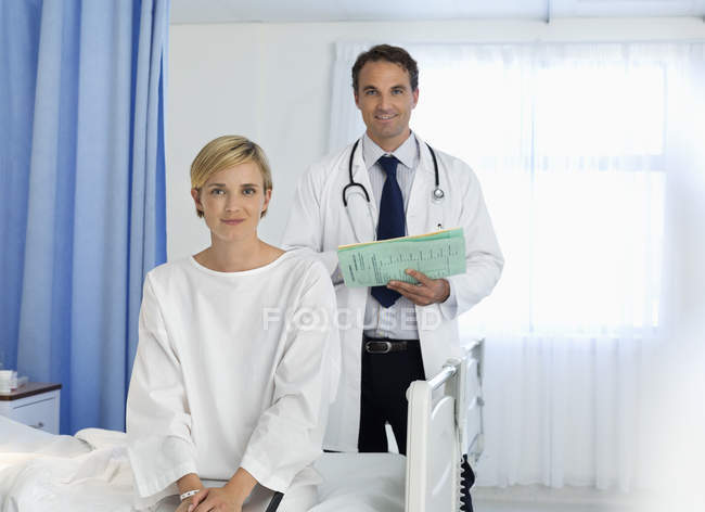 Médico y paciente sonriendo en la habitación del hospital - foto de stock