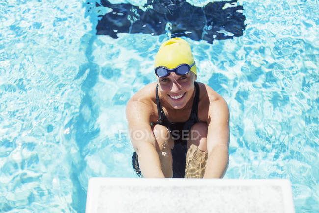 Portrait of smiling swimmer poised at starting block — Stock Photo