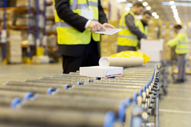 Trabajadores revisando paquetes en cinta transportadora en almacén - foto de stock