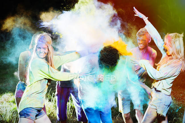 Friends throwing chalk dye on man at music festival — Stock Photo