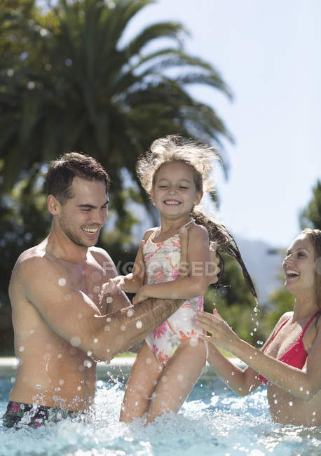 Feliz joven familia jugando en la piscina - foto de stock