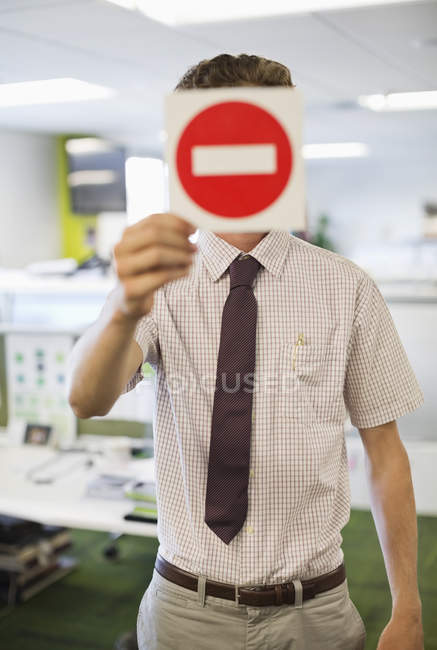 Empresario sosteniendo cartel de advertencia en la oficina - foto de stock