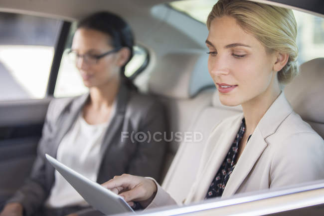 Donna d'affari che utilizza tablet digitale nel sedile posteriore dell'auto — Foto stock