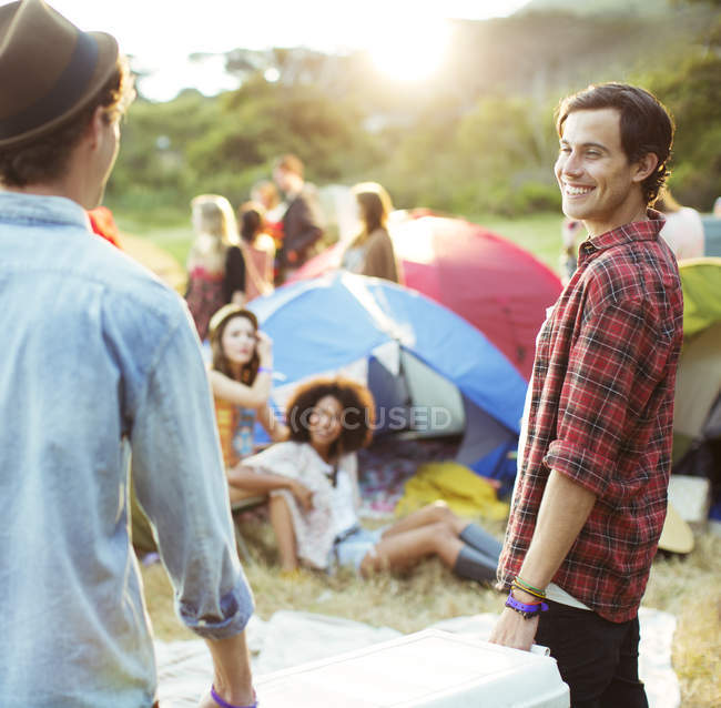 Men carrying cooler outside tents at music festival — Stock Photo