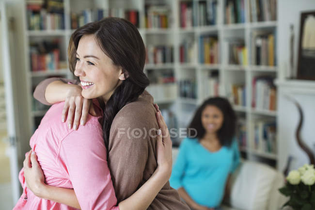 Mulheres abraçando na sala de estar — Fotografia de Stock