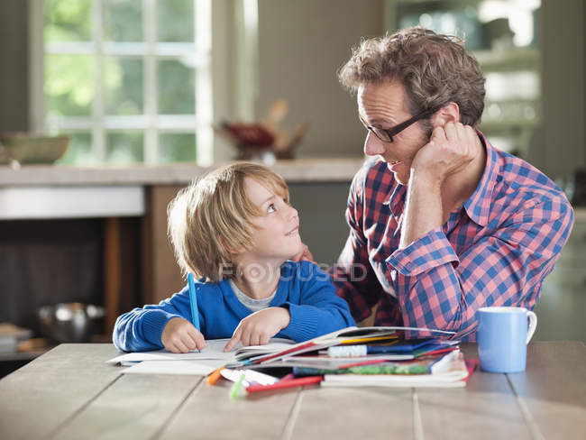 Father and son doing homework at kitchen table — Stock Photo