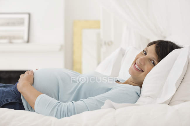 Pregnant woman laying on bed — Stock Photo