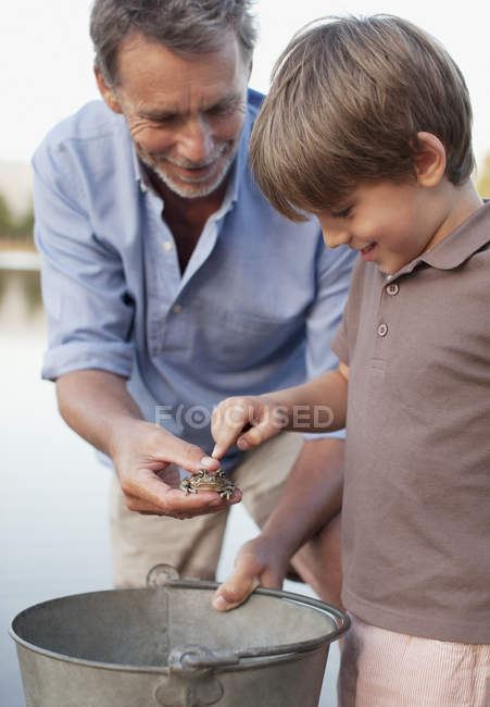 Grand-père et petit-fils avec grenouille et seau — Photo de stock