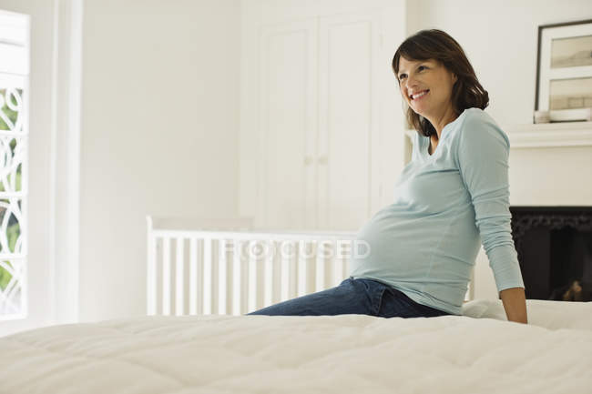 Mulher grávida sentada na cama — Fotografia de Stock