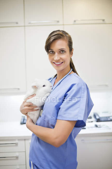 Smiling veterinarian holding rabbit in veterinary surgery — Stock Photo