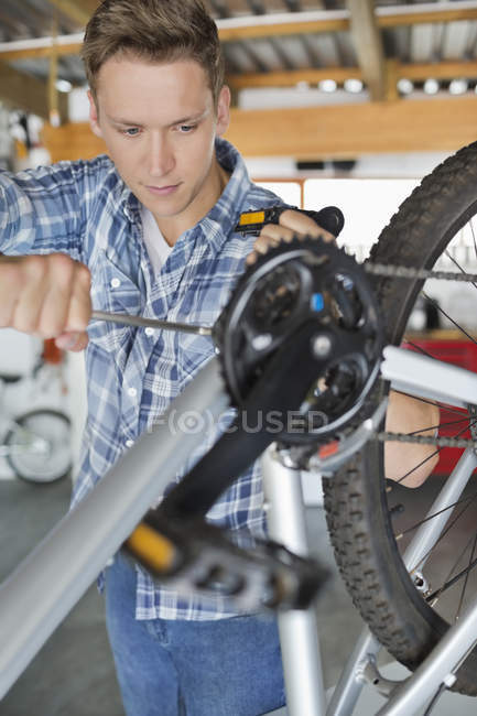 Homem caucasiano hábil trabalhando na bicicleta na loja — Fotografia de Stock