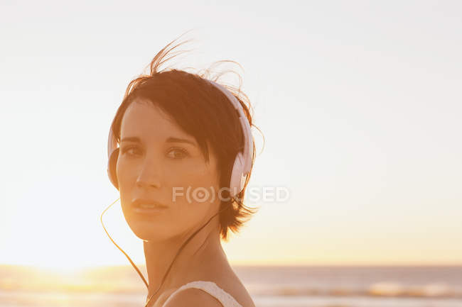Close up portrait of confident woman wearing headphones at beach — Stock Photo