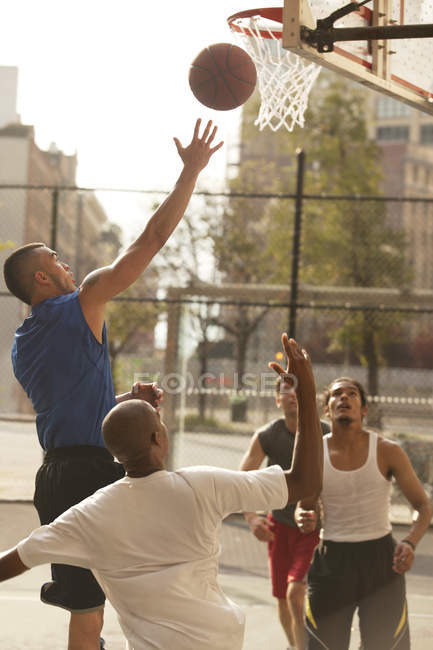 Hombres jugando baloncesto en la cancha - foto de stock