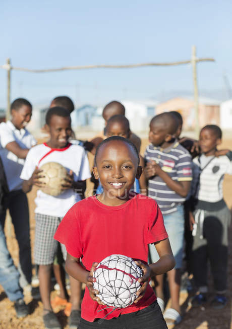 Meninos africanos segurando bolas de futebol no campo de sujeira — Fotografia de Stock
