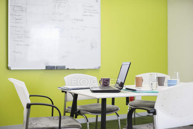 Laptop e xícaras de café na mesa de reunião no escritório moderno — Fotografia de Stock
