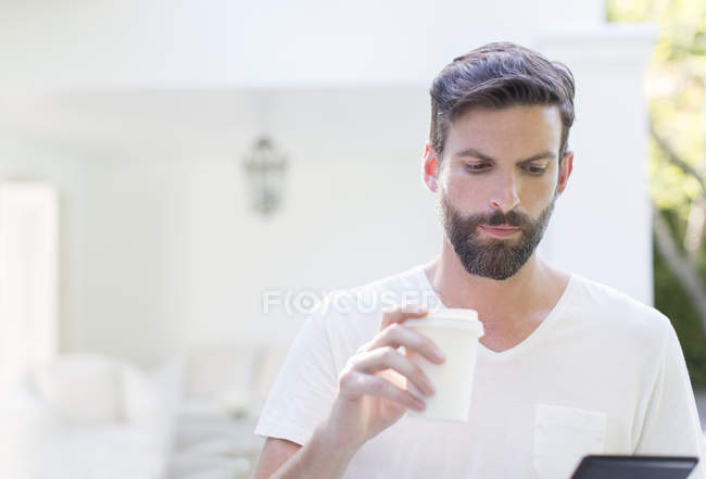 Homem bebendo café e usando tablet digital — Fotografia de Stock