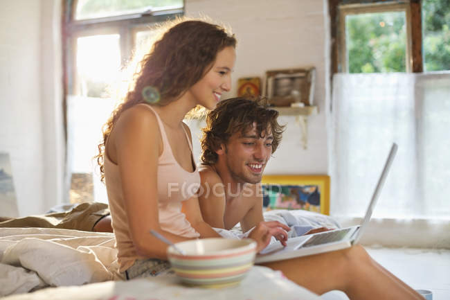 Paar benutzt Laptop gemeinsam im Bett — Stockfoto