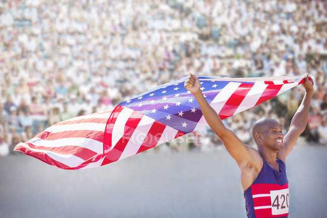 Pista e atleta de campo segurando bandeira americana no estádio — Fotografia de Stock