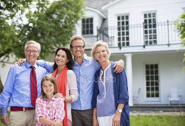 Familia sonriendo juntos fuera de casa - foto de stock