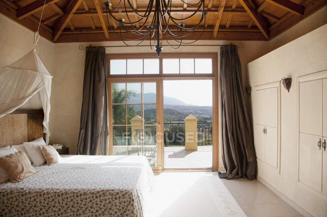 Кровать с балдахином и французские двери, ведущие на балкон в спальне — стоковое фото