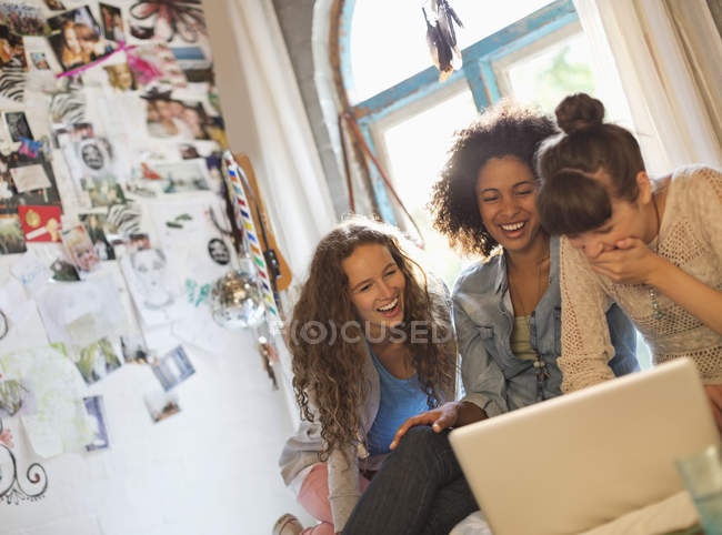 Las mujeres usando el ordenador portátil juntos en el dormitorio - foto de stock