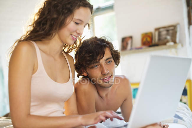 Couple utilisant un ordinateur portable ensemble au lit — Photo de stock