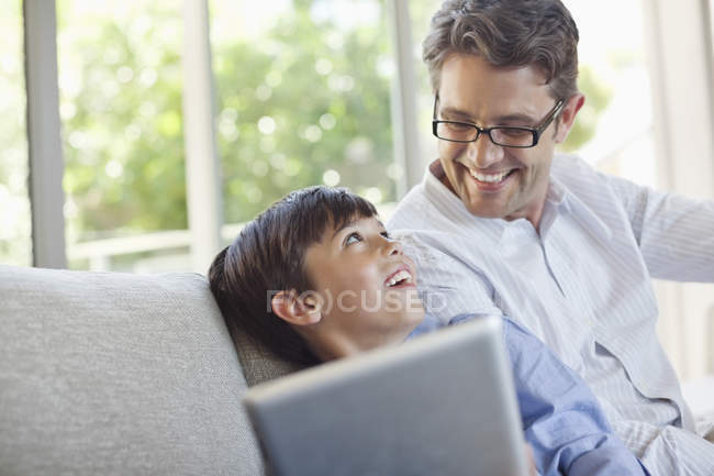 Père et fils utilisant une tablette sur le canapé — Photo de stock