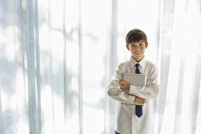 Мальчик в рубашке и галстуке держит планшетный компьютер — стоковое фото