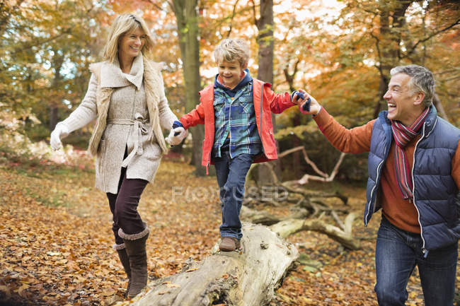 Heureux famille marche sur log dans parc — Photo de stock