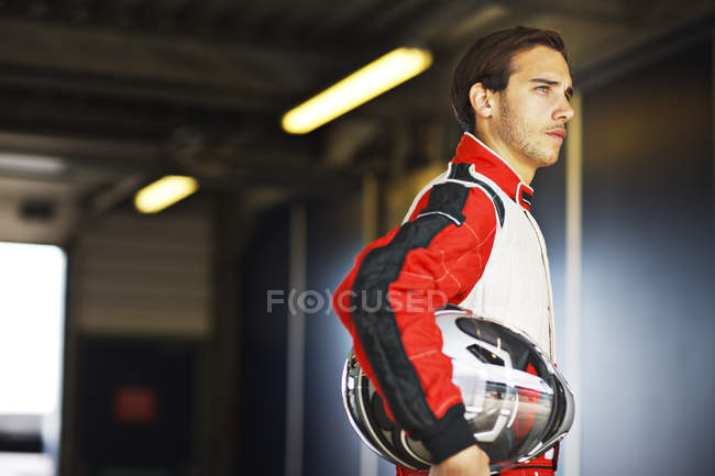 Racer holding helmet in garage — Stock Photo