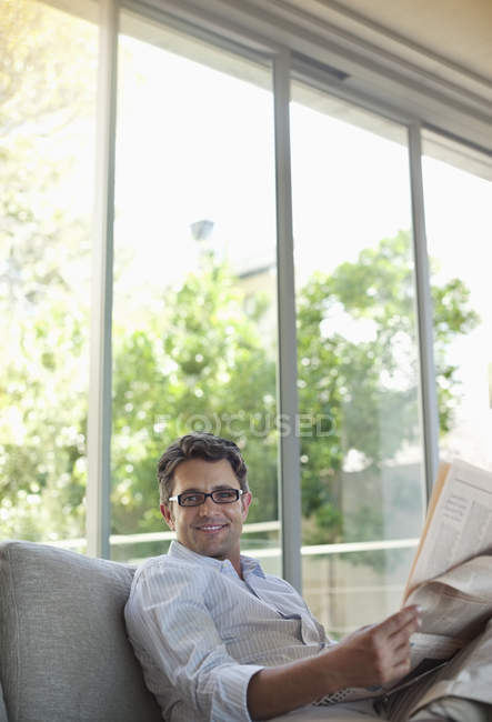 Homem lendo jornal no sofá — Fotografia de Stock