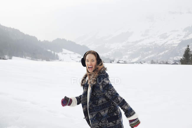 Retrato de mulher entusiasta correndo em campo nevado — Fotografia de Stock