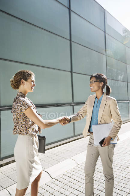 Businesswomen shaking hands on city street — Stock Photo