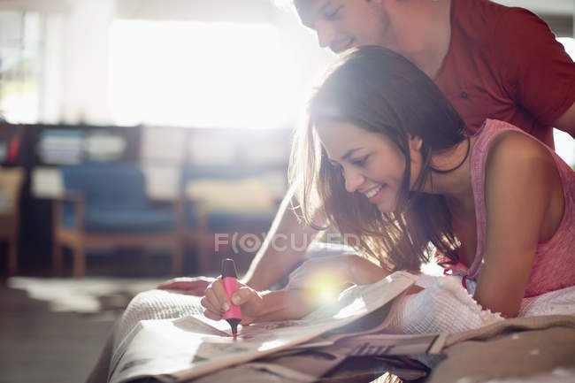 Пара читающих газету вместе на кровати — стоковое фото