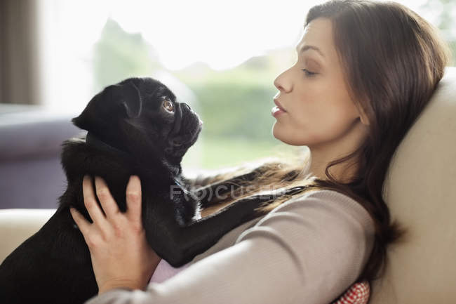 Женщина отдыхает с собакой на диване в современном доме — стоковое фото