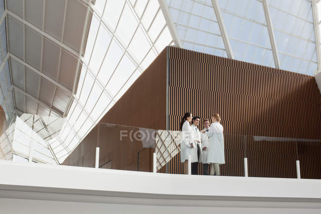 Médicos hablando en balcón moderno - foto de stock