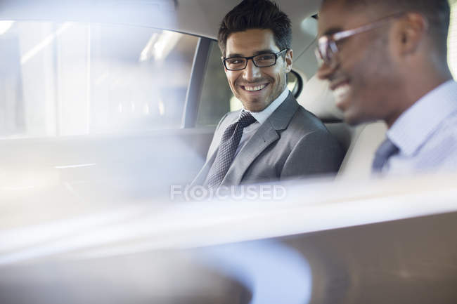 Hommes d'affaires assis sur le siège arrière de la voiture — Photo de stock